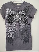 Front view of grey short sleeve top showing full winged fleur-de-lis graphic