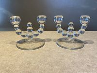 Pair of Imperial Glass Ball Stem Double Candlestick holders on a flat surface, no candles inserted, clear glass with connected spheres forming the stem.