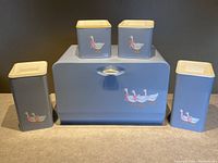 Photo showing the complete set including breadbox and four smaller square canisters, all in blue metal with white and red goose decals