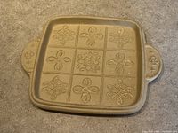 Top view of the stoneware baking pan showing 9 detailed knot design compartments and handle decorations.