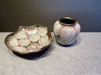 Side angle view of a maroon and gold West Germany pottery vase and a shell shaped bowl on a gray surface.