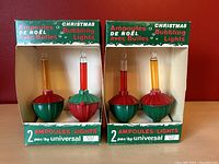 Two boxed pairs of vintage Christmas bubbler lights showing red and green bases with colored liquid glass tubes