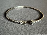 Full view of vintage sterling silver braided cuff bangle bracelet laying on black surface, showing open cuff design and decorative ends.