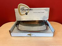 Vintage Glo-Hill Gourmates chrome holloware platter resting inside original box showing front panel logo and cut-out emblem