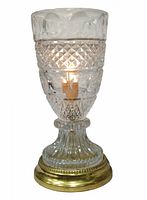 Front view of vintage crystal glass boudoir electric lamp lit, showing patterned glass urn shape and brass base.