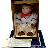 Matthew porcelain doll in sailor outfit seated inside original box with certificate and pamphlet in front.