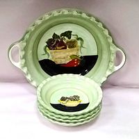 Front-facing image showing one large handled bowl in back and 4 smaller stacked bowls in front, with green interior and hand-painted vegetable basket design.