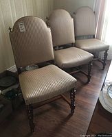 Four chairs lined up against wallpapered wall on hardwood floor