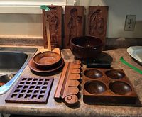 Full view of all wooden kitchen and decorative items on counter, showing gingerbread molds, bowls, trivet, rack and serving block.