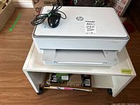 HP Envy printer on the white cart with wired mouse on top and supplies underneath