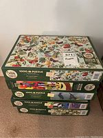 Stack of five Cobble Hill puzzle boxes showing front and side views, various designs visible