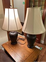 Pair of table lamps on wooden table, showing overall shape, shade, and cords