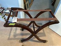 Top view of wooden folding luggage rack with two canvas straps and curved legs.