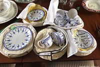 Overview of padded carriers containing plates, cups and saucers on wood table