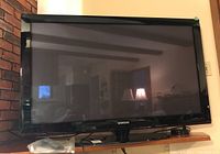 Front view of Samsung 50-inch TV showing screen and stand on wooden surface.