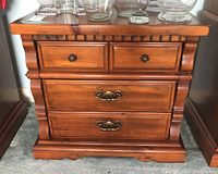 Front view of side table showing three drawers, two small on top and two larger below, with metal pulls and decorative molding.