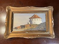 Frontal view of the framed oil painting showing the church on a hill.