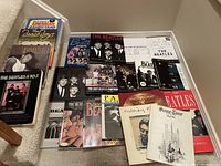 Grouped photo showing 21 Beatles and related music books arranged in a pile on carpeted stairs.
