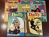 Five Dell comic books including three Daffy Duck and one Tom & Jerry, showing overall condition and artwork