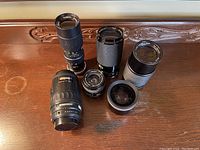 Top view of all six lenses arranged on a wooden surface showing various sizes and barrel designs.
