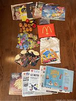 Photo of the full lot showing paper placemats, several McNugget toys, numerous sealed erasers, McDonald's t-shirt, plastic McDonald's bag, and collectible paper memorabilia.