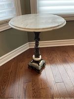 Full view of the Italian MCM round side table showing marble top and brass base on wood floor.