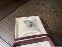 Top view of the ring inside a presentation box showing the oval Australian opal set in gold.