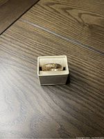 Ring in a small display box on wood table showing overall appearance.