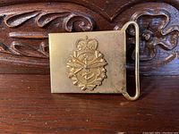 Front view of vintage brass belt buckle showing Canadian Armed Forces emblem with crossed rifles, anchor, crown, and laurel wreath.