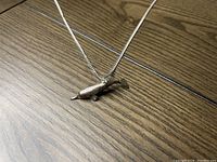 Close view of the sterling silver Baiji shaped pendant on the chain, showing the detailed dolphin shape and pointed snout.