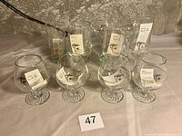 Set of 12 Petro Canada 1988 Olympics glasses, various styles, most with sales tags inside, arranged on table.
