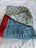 Sleeping bag folded on a bed showing red and blue exterior with hockey player patterned interior lining