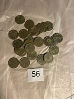 Multiple $25 Las Vegas casino dollar coins spread on a surface showing quantity and general wear.