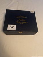 Closed box with Adeline name in gold lettering on navy background.