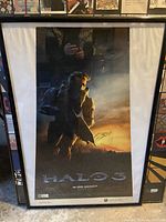 Framed Halo 3 poster showing Master Chief against sunset background, with reflection visible and A-frame style fitting 41"x28" frame.
