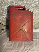 Photo of vintage red metal gas can marked 'G U.S.A.' showing wear.