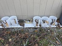 Full view of multiple steel cables and chains arranged with hooks on white containers, showing a variety of sizes and hook types.