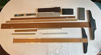 Top-down view of the entire lot showing wooden rulers, T-squares, rulers, logarithmic rulers in cases, and calculators.