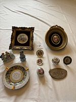 Full view of all antique porcelain pieces on white cloth background including frames, plates, figurines, and trinket boxes.