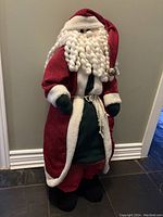 Photo of standing Santa figure approximately 1 meter tall showing red coat with white trim, braided beard, and black mittens