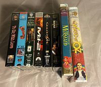 Photo showing the spines of eight sealed VHS tapes in a row: To Sir, With Love, Superman 3, Robin Hood, M:I-2, Goldeneye, Star Wars 1, The Little Mermaid, The Wizard of Oz