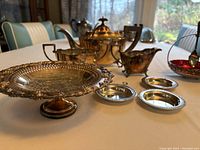 Full view of six-piece silver serving set arranged on table.