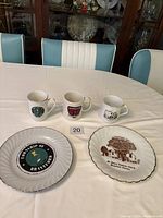 Photo showing two souvenir plates and three commemorative cups on dining table