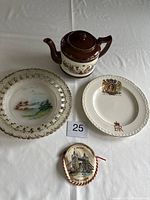 Top view of all four items showing teapot, two plates, and Tower Bridge ornament with lot number.