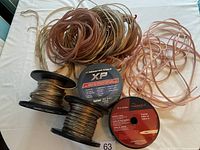 Image showing multiple spools of speaker wire and loose lengths spread on a white surface