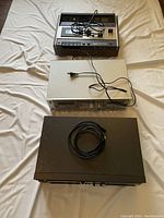 All three tape decks laid out on cloth surface: Akai GXC-46D on top, Technics RS-TR265 in the middle, Technics M202 at bottom with power cords visible