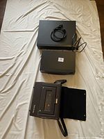 Photo of all three VHS players stacked on a light fabric background, showing front and top views.