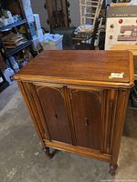 Wooden radio cabinet with double front doors and refinished surface, showing top and front sides.