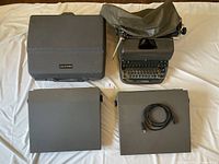 Overview photo displaying four vintage typewriters: Eaton Viking in case, two Panasonic R200 models with cords, Remington Rand with cover.