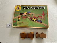 Top view of vintage Holzbahn 1983 train set box with wooden train cars and two wooden cars in front.